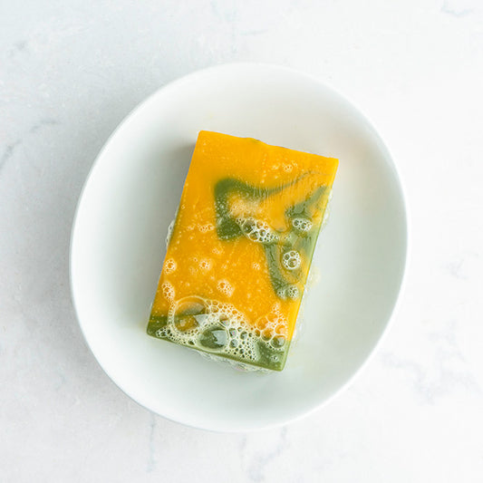 Spearmint Lemongrass bar soap covered in bubbles on a soap dish
